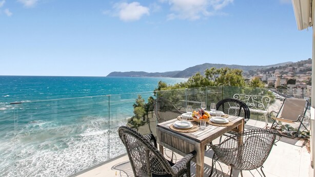 A balcony with a table set for dining, overlooking a coastal view with the sea and distant hills. - Attico Giancardi - Beachfront Sea-View Terrace, Alassio, Italy (Alassio)