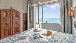 A bedroom with a bed, a window with a view of the sea, a wardrobe, and a door leading to a balcony. - Attico Giancardi - Beachfront Sea-View Terrace, Alassio, Italy (Alassio)