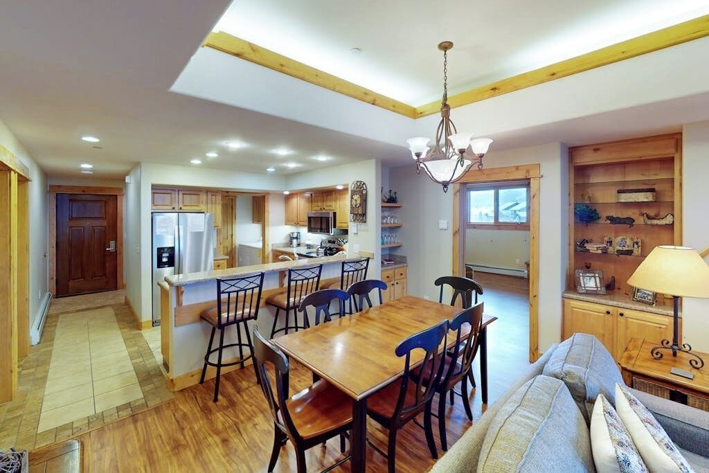 Una cocina moderna con armarios de madera, una isla central y un comedor con sillas.