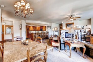 A spacious living area with a dining table, chairs, a fireplace, and a ceiling fan. - Ski-in/out mountain condo with W/D, free WiFi, pool, & hot tub (Steamboat Springs)