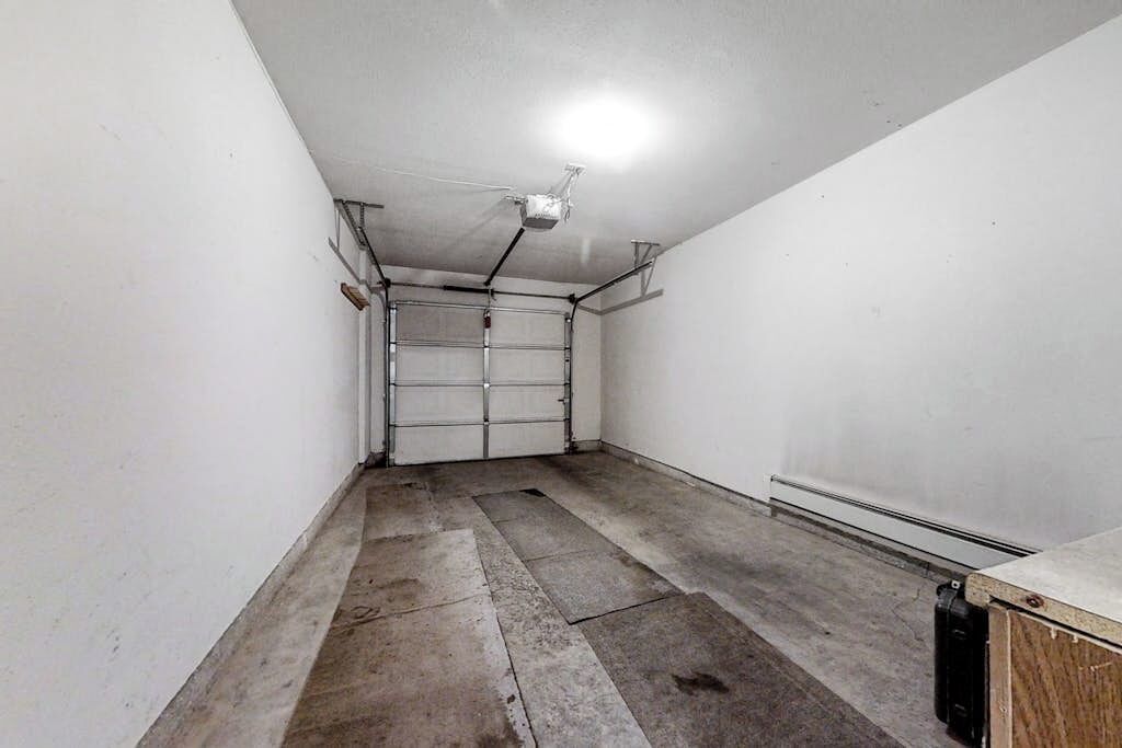 A narrow hallway with a garage door, concrete floor, and a ceiling light fixture.