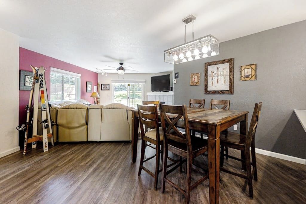 A dining area with a wooden table and chairs, a ceiling fan, and a television on a stand.