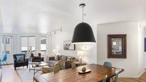 Amplia sala de estar con una mesa de comedor de madera, una lámpara colgante negra grande y un conjunto de sofá.