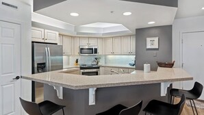 Una cocina moderna con una isla central, electrodomésticos de acero inoxidable y una pared de acento gris oscuro.