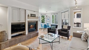 Una sala de estar moderna con chimenea, un televisor de pantalla plana, una mesa de centro de vidrio y un sofá.
