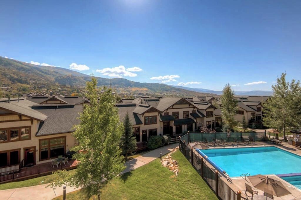 A resort with multiple buildings, a swimming pool, and a mountainous backdrop.