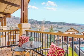 Ein Balkon mit Tisch und Stühlen, der einen schönen Blick über ein Tal und ein Gewässer bietet.