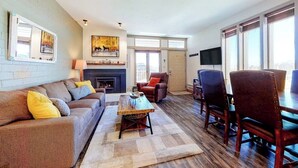 Ein Wohnzimmer mit Sofa, Couchtisch, Kamin, Fernseher und Essbereich.