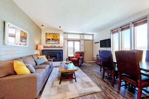 Ein Wohnzimmer mit Sofa, Couchtisch, Kamin, Fernseher und Essbereich.