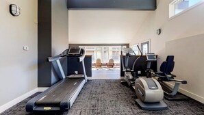 Ein Fitnessraum mit Laufbändern, Crosstrainern und Teppichboden.
