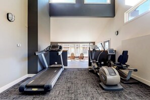 Ein Fitnessraum mit Laufbändern, Crosstrainern und Teppichboden.