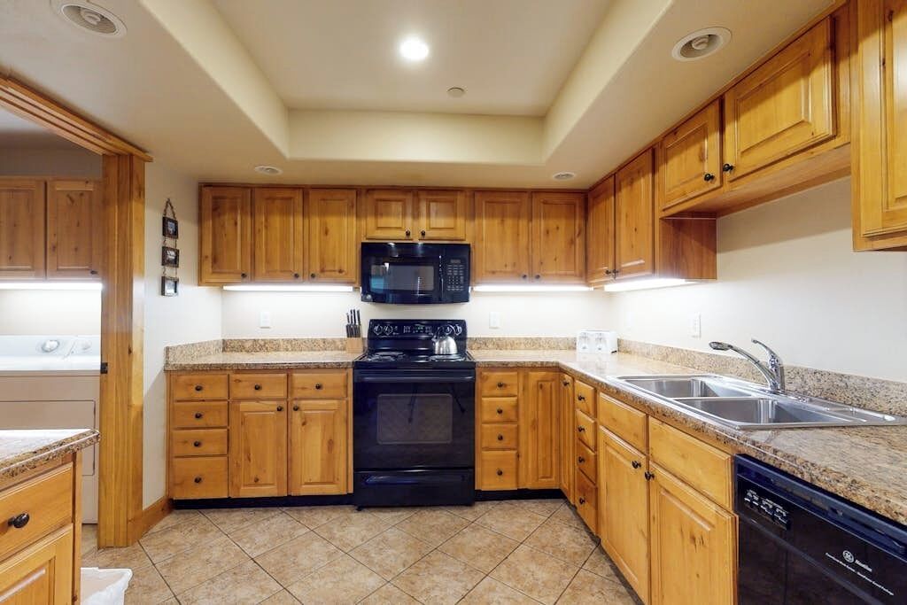 A kitchen with wooden cabinets, a black stove, a microwave, and a dishwasher.