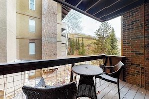 Ein Balkon mit Korbmöbeln und Blick auf ein Gebäude und Bäume.