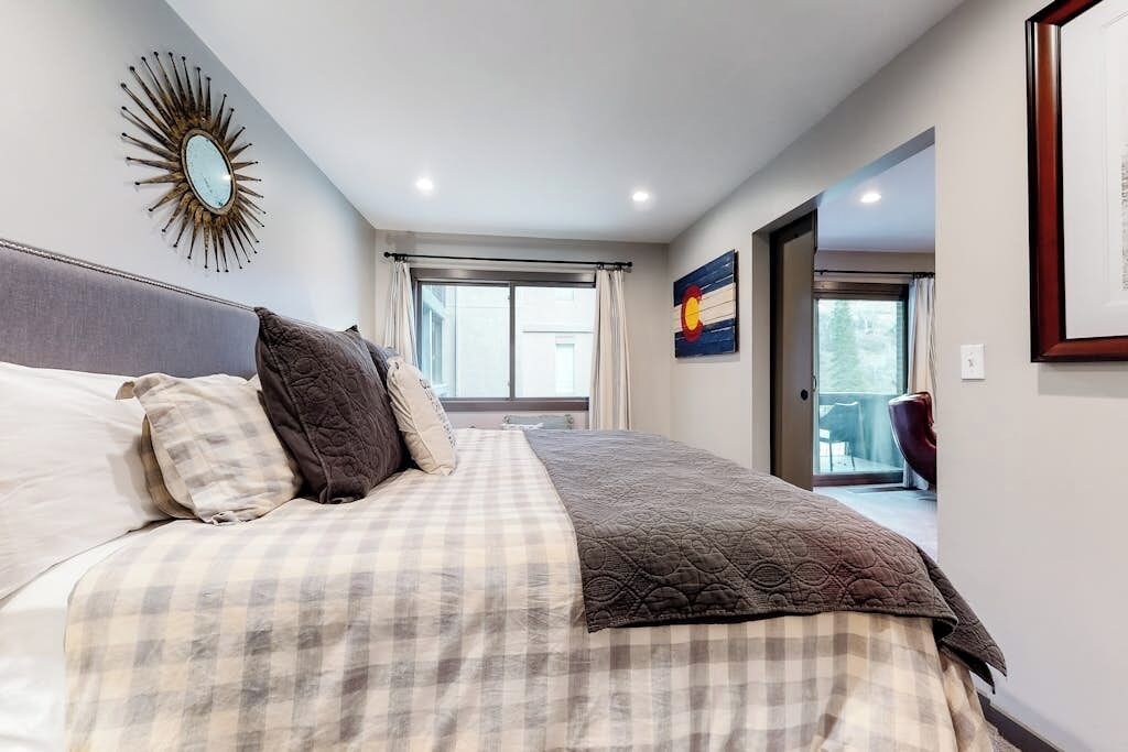 Ein Schlafzimmer mit einem Bett, einem Fenster, einer Tür zu einem Balkon und einem an der Wand befestigten Spiegel.