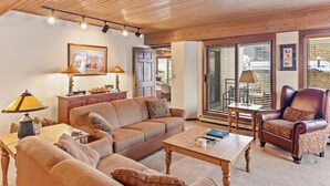 Un salon confortable avec un canapé, un fauteuil, une table basse et des lampes.