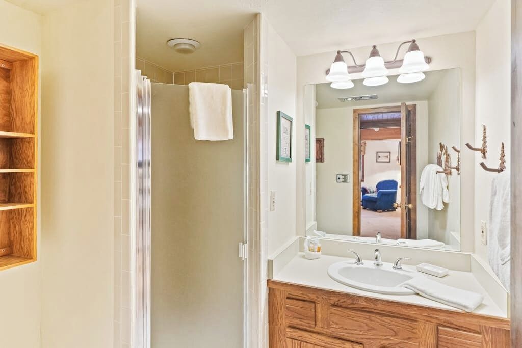 Une salle de bain avec un meuble-lavabo en bois, un grand miroir et une douche.