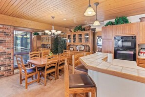 A wooden interior with a dining area, kitchen, and a brick wall. - Mountain view condo w/ fireplace, W/D, shared hot tubs/firepit, steps to gondola (Steamboat Springs)