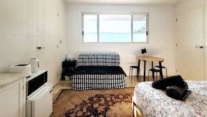 Ein Schlafzimmer mit Bett, einer Couch, einem kleinen Tisch mit Stühlen, einem Fenster mit Aussicht und einer Küchenzeile.