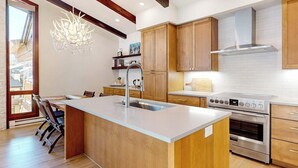 Una cucina moderna con mobili in legno, un piano cottura in acciaio inossidabile e una grande isola con lavello.