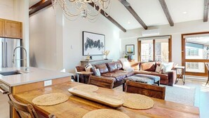 Un'ampia zona giorno con un tavolo da pranzo in legno, divani in pelle e un'ampia finestra.