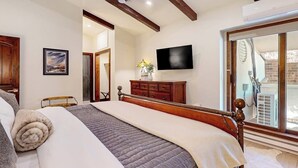 Camera da letto con un letto, una testiera in legno, una TV a schermo piatto, un comò e una finestra con vista.