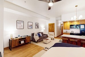 Ein modernes Apartment mit Wohnbereich, Küchenzeile und einem großen Bett.