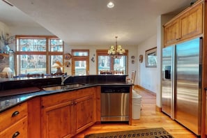 A kitchen with wooden cabinets, stainless steel appliances, and large windows. - Large townhouse with heated pool, shared hot tub, & balcony - walk to gondola (Steamboat Springs)