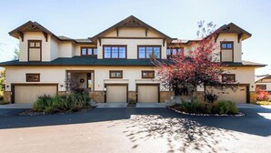A large, two-story house with a symmetrical facade, multiple garage doors, and a well-maintained front yard with a tree. - Walk-to-lift townhome w/ fireplace, laundry & resort pool/hot tubs/gym/firepit (Steamboat Springs)