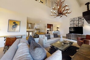 A modern living room with a sofa, coffee table, and a chandelier. - Upscale chic condo close to slopes with hot tubs & winter shuttle (Steamboat Springs)