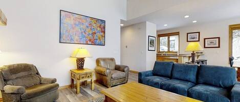 Un salon comprenant un canapé, deux fauteuils, une table basse et un tapis.