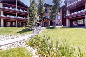 Ein mehrstöckiges Hotel mit einem zentralen Eingang, Außenbereich zum Sitzen und einem gepflegten Rasen.