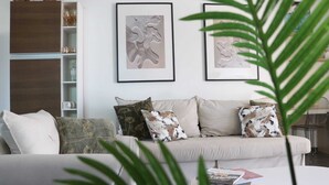 A living room with a sofa, cushions, a bookshelf, and framed artwork on the wall. - Charming 3-bedroom, 2-bathroom house with AC in quiet neighborhood in Curaçao (Willemstad)