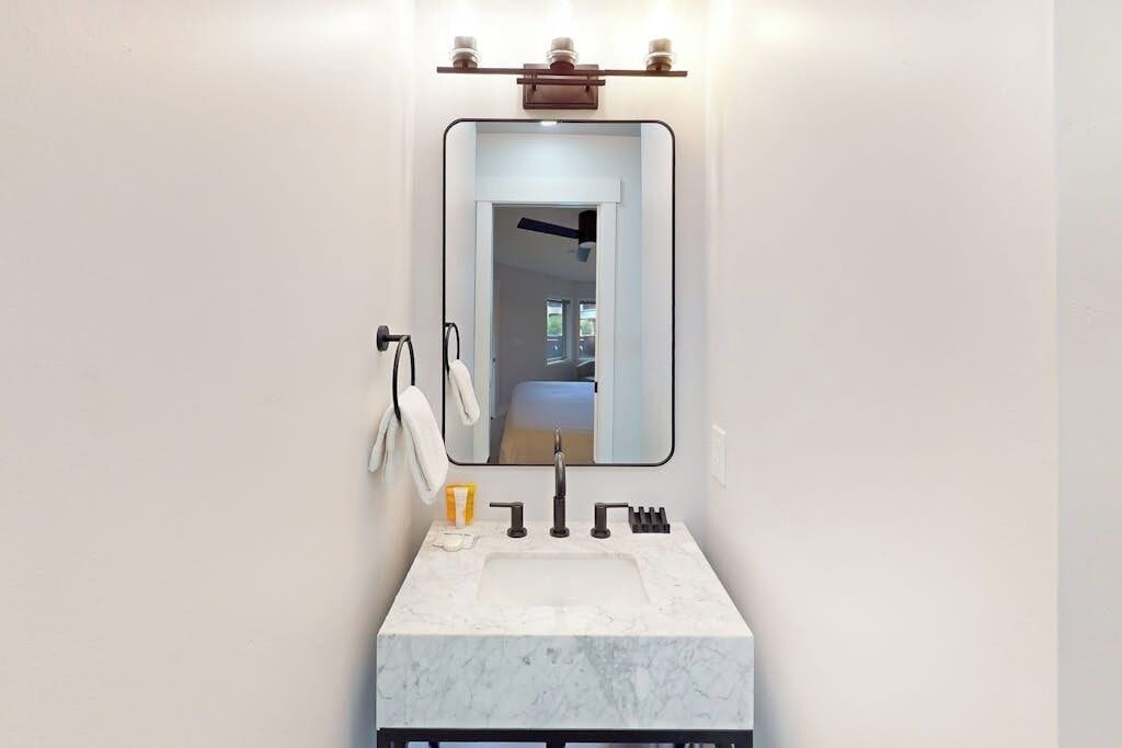 Un bagno con un lavabo in marmo bianco, uno specchio e un portascopino.