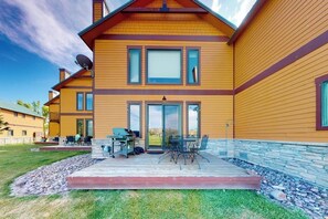 A modern two-story house with a deck, outdoor seating, and a satellite dish.