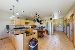 A spacious kitchen with a central island, stainless steel appliances, and pendant lighting.
