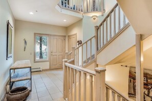 Ein mehrgeschossiges Interieur mit Treppe, einer Sitzbank und einer zur Außenwelt führenden Tür.