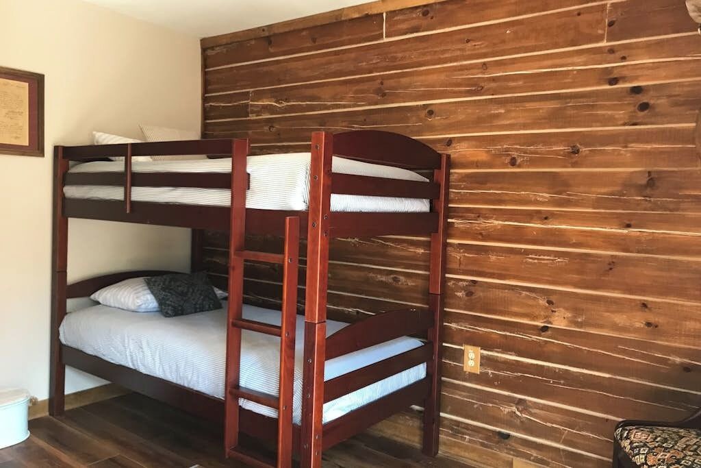 Una cama litera con cabecera y pared de madera con tablones horizontales.