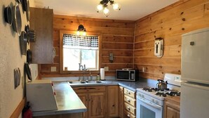 Eine Küche mit Holzwänden, einer Mikrowelle, einem Herd und einem Kühlschrank.