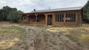 Eine Holzhütte mit Veranda, großen Fenstern und einem Metall-Dach.