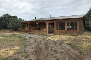 A wooden cabin with a porch, large windows, and a metal roof.