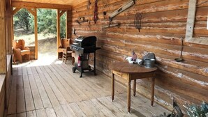 Eine Holzterrasse mit Grill, Stühlen und einem Tisch, auf dem eine amerikanische Flagge steht.