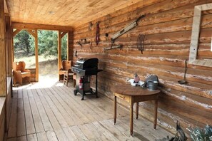 A wooden deck with a grill, chairs, and a table with an American flag.