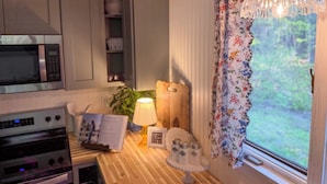 Ett kök med mikrovågsugn, ugn och ett fönster med blommiga gardiner.