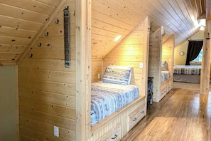 Una cabaña de madera con habitación en el altillo, baño pequeño y ventana visible.