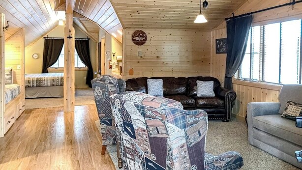 Une pièce chaleureuse avec un plafond en bois, un canapé, un divan et un lit.