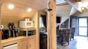 Un intérieur en bois comprenant un coin cuisine, une table à manger avec des chaises et une porte visible donnant sur une autre pièce.