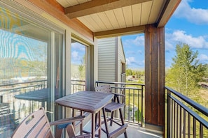 Een balkon met een tafel en stoelen, uitzicht op het landschap en een houten balustrade.
