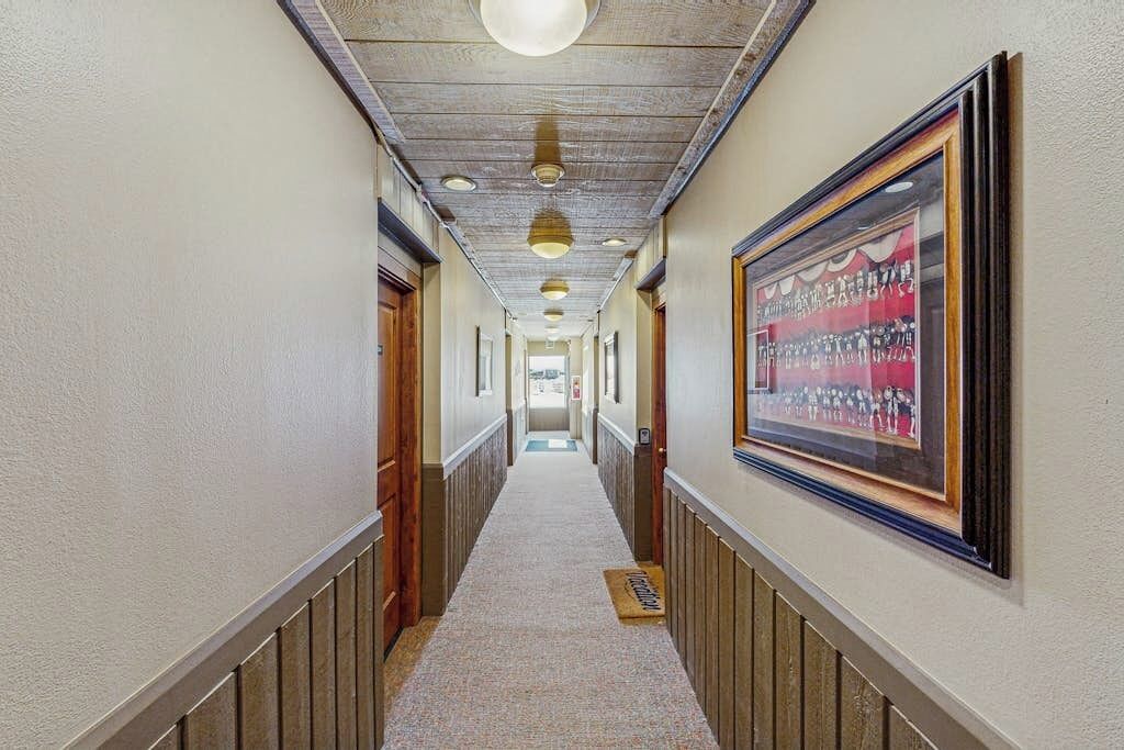 A hallway with wooden paneling, a framed picture on the wall, and a carpeted floor.