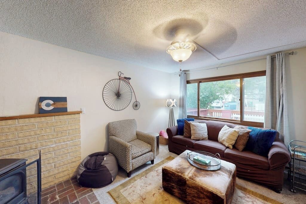 A living room with a fireplace, a sofa, a patterned armchair, a coffee table, and a bicycle decoration on the wall.