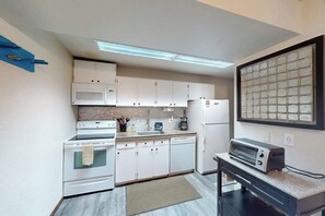 Eine kompakte Küche mit weißen Schränken, einer Mikrowelle, einem Herd, einem Geschirrspüler und einem Toaster.